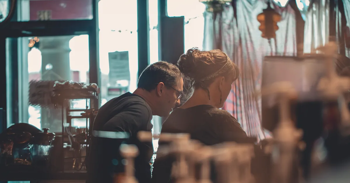 Two small business owners talking across a table while discussing a web design quote.