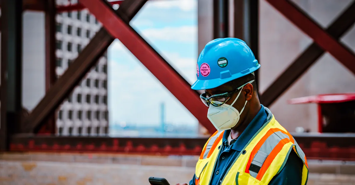 A contractor checking their phone on a job site, representing digital marketing for contractors.