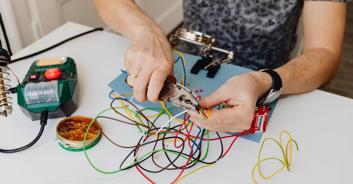 A technician cutting and organising colored electrical wires.