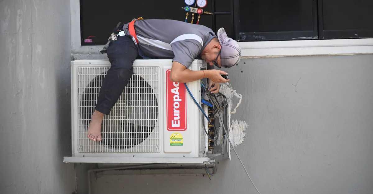 A technician repairing an outdoor air conditioning unit.