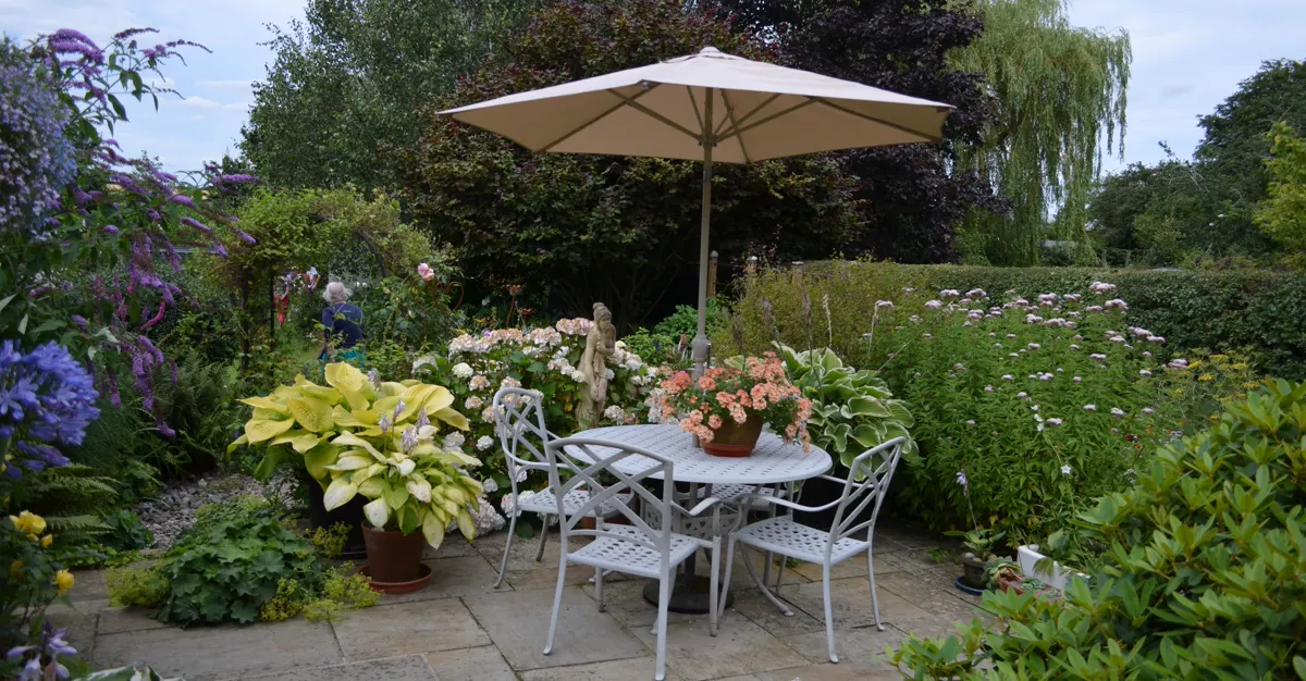 A finished garden patio with a table, chairs and umbrella, the kind of transformation a landscaping portfolio should show.