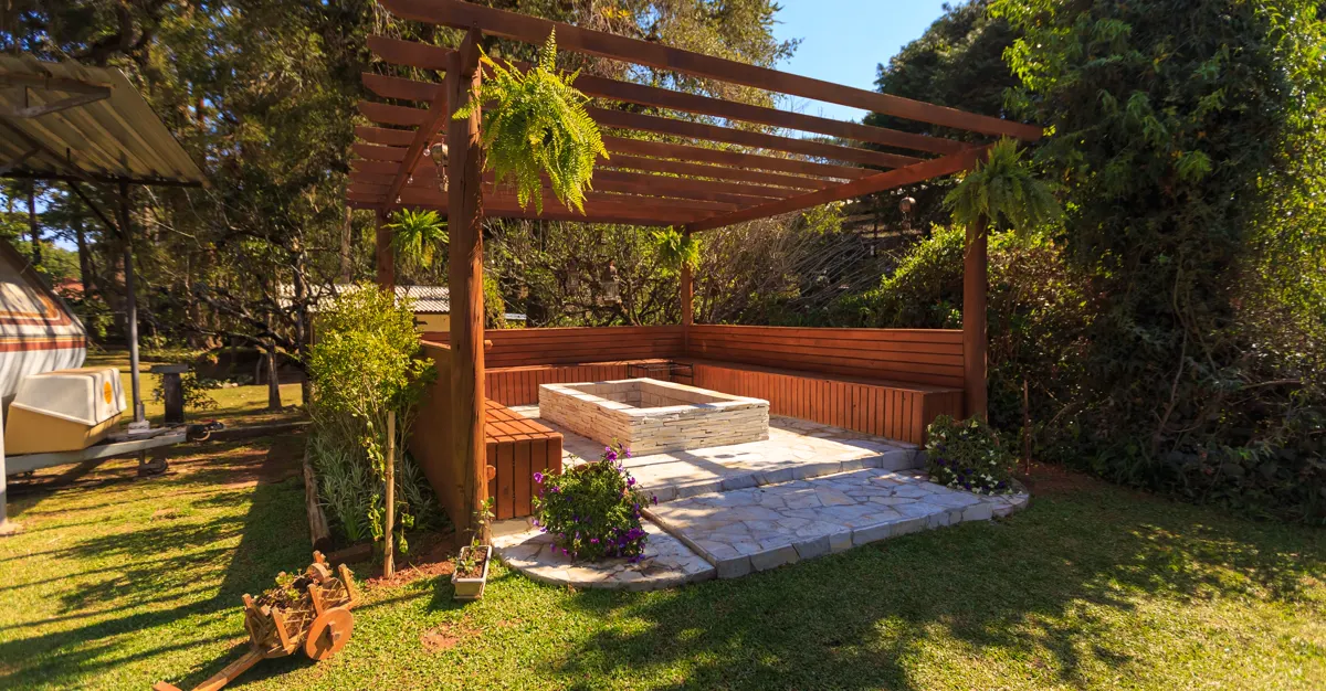 A wooden gazebo in a landscaped garden with lush green planting.