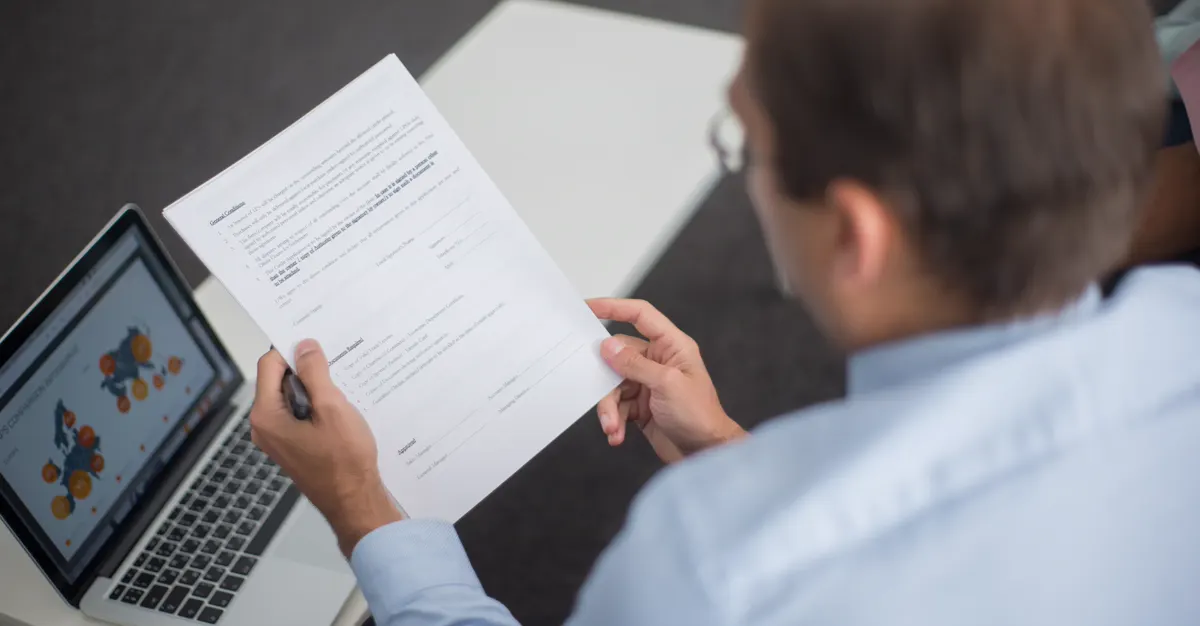 A person reviewing documents beside a laptop, comparing contractor lead generation options.