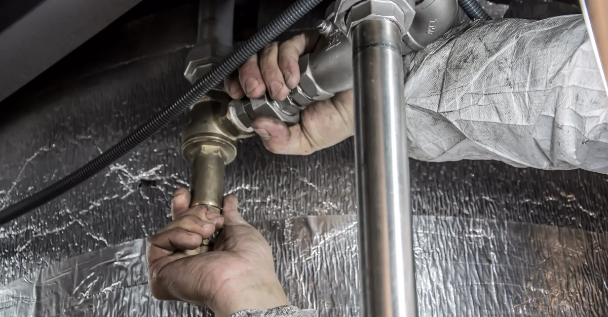 A plumber's hands fitting steel pipe, representing the trade behind a plumbing website.