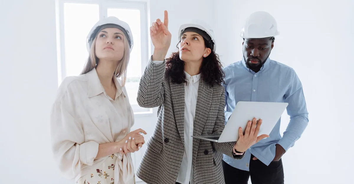 A contractor team in hard hats reviewing plans on a laptop, representing website design for contractors.